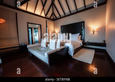 Lussuosa camera da letto in villa sull'acqua alle Maldive con letto king size e atmosfera spa Foto Stock