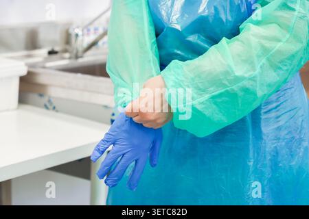 Operatore sanitario che indossa i dispositivi di protezione individuale all'interno di una struttura sterile, sottolineando l'importanza vitale del protoco di igiene professionale Foto Stock