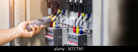 Tester di lavoro per elettricisti che misura la tensione e la corrente della linea elettrica di alimentazione nel controllo elettrico dell'armadio. Foto Stock