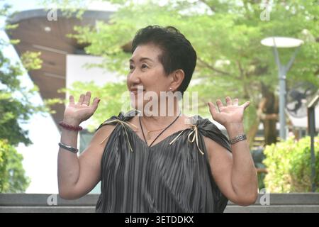donna anziana forte e sana in posa e sorridente nel giardino del centro commerciale comunitario Foto Stock