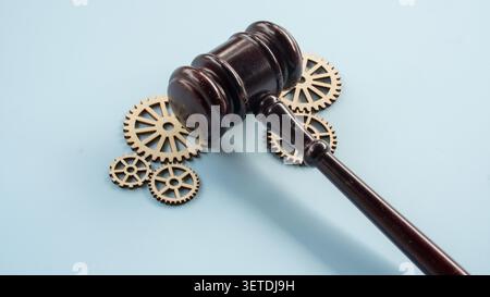 Primo piano di un martelletto di legno che colpisce su ingranaggi in miniatura su una superficie blu Foto Stock
