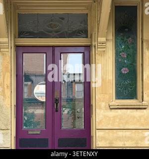 Doppie porte frontali viola con finestra decorativa sullo specchio di poppa su un edificio storico. Foto Stock