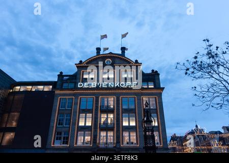 AMSTERDAM, PAESI BASSI - 10 NOVEMBRE 2025: La facciata illuminata dei grandi magazzini De Bijenkorf, decorata con luci natalizie al crepuscolo di Amsterdam Foto Stock