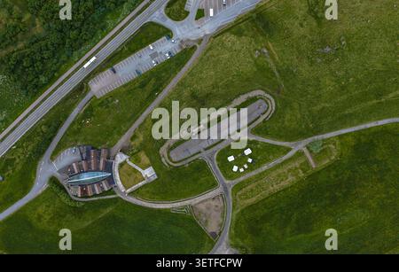Vista aerea con drone di una moderna struttura sportiva con piscina, aree parcheggio e campi verdi circostanti a Lofoten, Norvegia. Lussureggiante Foto Stock