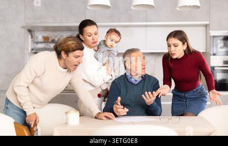 Persone di diverse generazioni discutono tra loro e mostrano a un padre maturo come compilare correttamente i documenti Foto Stock