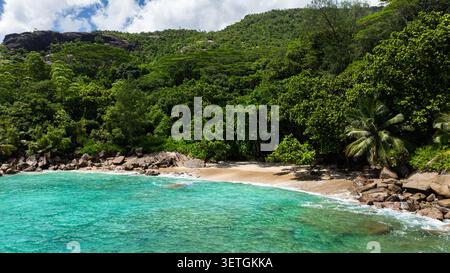 Vista aerea della baia turchese circondata da verdi colline con barche che navigano nelle acque cristalline. Seychelles, Mahe. Foto Stock