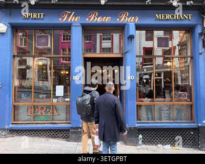 Persone che entrano al Bow Bar in Victoria Street. Edimburgo, Scozia, Regno Unito. Tradizionale facciata da pub con legno dipinto di blu e grandi finestre in vetro. Foto Stock
