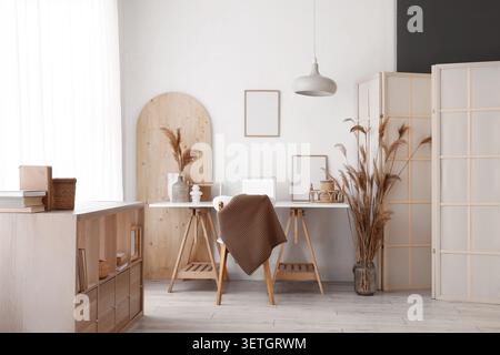 Moderno ambiente di lavoro con laptop, scaffalatura e schermo pieghevole Foto Stock