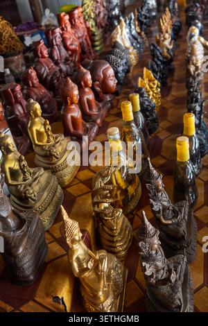 Varie statue di Buddha e bottiglie di vino di serpente esposte in vendita in un mercato asiatico Foto Stock