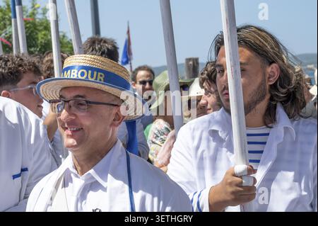 Un batterista sorridente che indossa un caratteristico cappello di paglia accanto a un giovane lancer con una tradizionale camicia bianca da marinaio riflette l'atmosfera emotiva e festosa Foto Stock