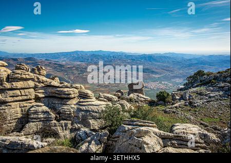 Formazioni rocciose calcaree e paesaggio carsico a El Torcal vicino ad Antequera in Andalusia, Spagna, con un'ampia vista su una valle asciutta, un villaggio lontano e. Foto Stock