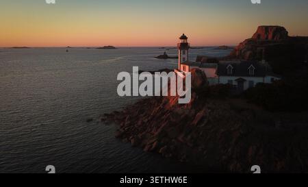 Vista aerea del faro Phare de l'ile Louet arroccato su scogliere rocciose al tramonto con calme acque marine a Carantec, Bretagna, Francia. Foto Stock