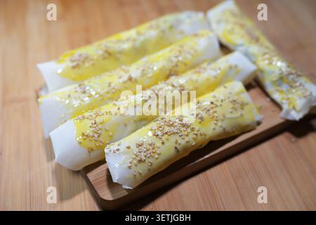 Involtini di pasta yufka ripieni crudi cosparsi di semi di sesamo, pronti per essere fritti in profondità come pasticceria sigarra su un tavolo da cucina in legno, focalizzazione selezionata, n Foto Stock
