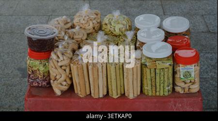 Varietà di spuntini asiatici e biscotti esposti in vendita in Street Market Stall in Cambogia Foto Stock