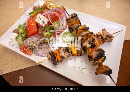 Spiedini di suino alla griglia con insalata greca fresca Foto Stock