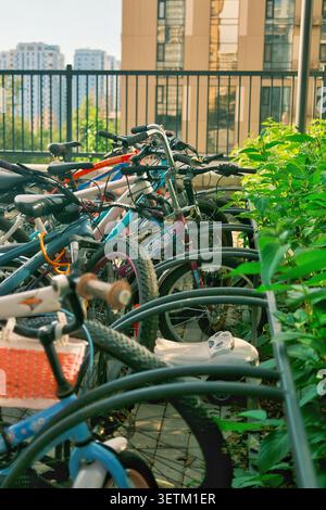 Più biciclette parcheggiate in un cortile residenziale vicino a moderni condomini. Concetto di trasporto sostenibile, mobilità urbana Foto Stock