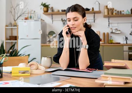 La freelance si impegna in una conversazione importante mentre è circondata dal suo spazio di lavoro Foto Stock