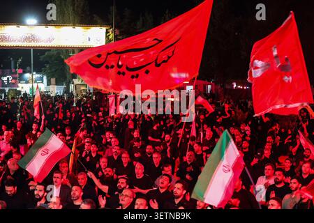 23 giugno 2026, Teheran, Iran: I sostenitori ondeggiano bandiere nazionali e religiose iraniane durante un raduno organizzato dallo stato illuminato in rosso in Iran. Il raduno seguì la firma del 18 giugno di un memorandum d'intesa ad interim del presidente degli Stati Uniti Donald Trump e del presidente iraniano Masoud Pezeshkian, volto a porre fine al conflitto regionale iniziato con gli scioperi USA-israeliani sull'Iran il 28 febbraio. Il 22 giugno, Washington ha temporaneamente allentato le sanzioni sulle esportazioni di petrolio iraniano dopo che il vicepresidente degli Stati Uniti JD Vance ha detto che Teheran aveva accettato di invitare gli ispettori dell'Agenzia internazionale per l'energia atomica di nuovo nel conteggio Foto Stock