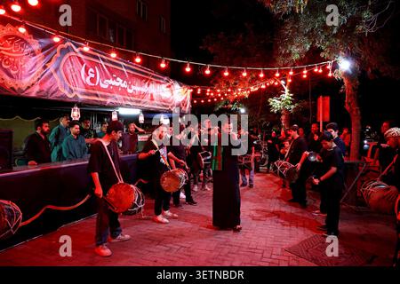 23 giugno 2026, Teheran, Iran: Gli uomini suonano la batteria durante un raduno organizzato dallo stato in Iran, dove luci rosse e striscioni sono esposti lungo una strada. Il raduno seguì la firma del 18 giugno di un memorandum d'intesa ad interim del presidente degli Stati Uniti Donald Trump e del presidente iraniano Masoud Pezeshkian, volto a porre fine al conflitto regionale iniziato con gli scioperi USA-israeliani sull'Iran il 28 febbraio. Il 22 giugno, Washington ha temporaneamente allentato le sanzioni sulle esportazioni di petrolio iraniano dopo che il vicepresidente degli Stati Uniti JD Vance ha detto che Teheran aveva accettato di invitare gli ispettori dell'Agenzia internazionale per l'energia atomica di nuovo nel paese Foto Stock