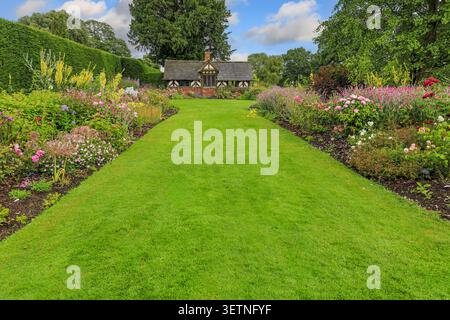 Il confine erbaceo con il Tea Cottage sullo sfondo ai giardini di Arley Hall, Cheshire, Inghilterra, Regno Unito Foto Stock
