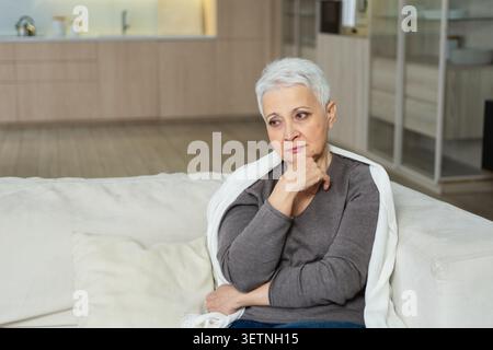 Triste stanco malato solo deluso anziana donna seduta a casa da solo. Nonna matura infelice che sperimenta dolore relativa morte cattiva notizia. Stressato anziana che soffre di solitudine Foto Stock