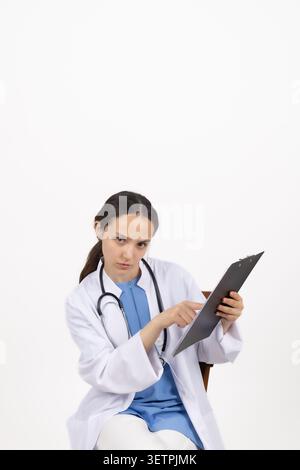 Giovane donna che scrive su carta per cartelle su sfondo bianco Foto Stock