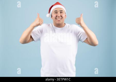 Giovane allegro che indossa il cappello di Babbo Natale che punta le dita verso l'alto eccitatamente Foto Stock
