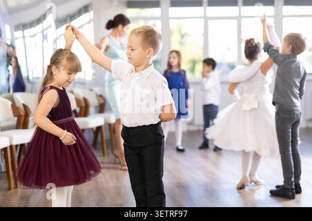 Entusiasti bambini preadolescenti che ballano valzer a coppie nella scuola di danza Foto Stock