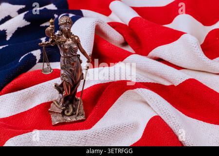La statua della giustizia si erge sulla bandiera americana piegata, simbolo dell'ordine pubblico durante l'ufficio lavori Foto Stock