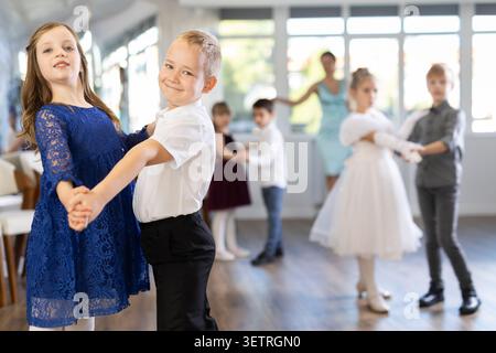 Entusiasti bambini preadolescenti che ballano valzer a coppie nella scuola di danza Foto Stock