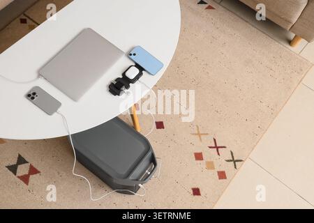 Spazio di lavoro moderno con laptop, smartphone, smartwatch e auricolari wireless su un tavolo bianco Foto Stock