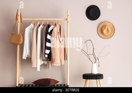 Appendiabiti minimalista con outfit neutri e cappelli decorativi a parete Foto Stock
