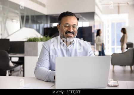 Uomo d'affari che guarda contenuti online su un notebook e ride Foto Stock