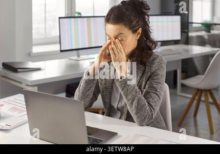 Contabile donna stressata al laptop in ufficio, crunch dei dati e sovraccarico finanziario Foto Stock