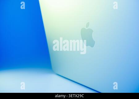 Lettonia, Jurmala - 20.06.2026: Scatola di nuovo Macbook NEO. Sfondo blu brillante con un primo piano di un computer portatile Apple che mostra il logo sulla custodia Foto Stock