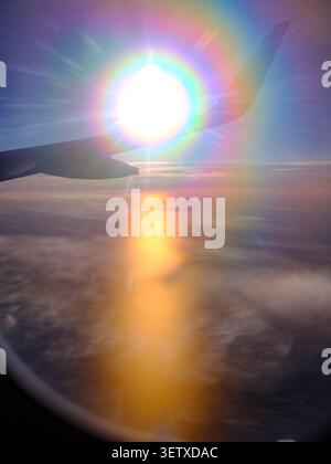 Dalla finestra dell'aereo si può ammirare un suggestivo sole tramontato sulla Svezia durante il sole di mezzanotte sull'ala dell'aereo che sfoggia colori arcobaleno nella fotocamera Foto Stock