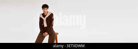 Il giovane uomo si distingue per gli abiti eleganti e raffinati, che incarnano la moda moderna in un ambiente sereno. Foto Stock