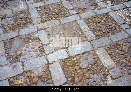 Un primo piano dei percorsi antichi a motivi mosaici di Siviglia, un misto di ciottoli e ghiaia fluviale. Le pietre precedenti sono state migliorate nel XX secolo. Foto Stock