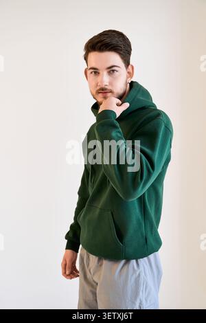 Un giovane con un abbigliamento casual mostra la sua barba e il suo senso della moda in uno studio Foto Stock
