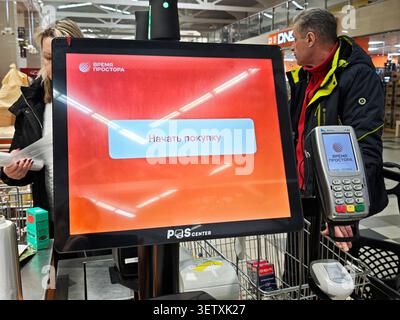 Kirov, Russia - 8 febbraio 2026: I clienti utilizzano la macchina self-checkout per il pagamento mentre fanno shopping in un supermercato durante le ore di punta della giornata. Foto Stock