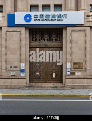 Ingresso ornato alla storica China Construction Bank al 50 di Jiujiang Road a Shanghai, Cina, con porte decorative in legno su una classica facciata in pietra Foto Stock