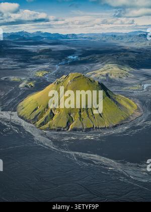 Veduta aerea di Maelifell, una vibrante montagna vulcanica coperta di muschio verde che sorge dalle scure pianure vulcaniche di sabbia a Kirkjubaejarklaustur, Skaftarhreppur Foto Stock