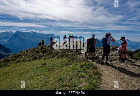 Gli escursionisti si riuniscono su una cima rocciosa della cresta di Stoos, stagliata contro un panorama di vette frastagliate Foto Stock