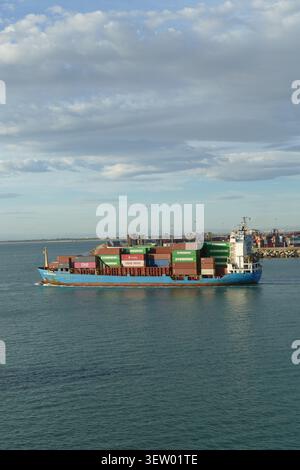 VALENCIA, SPAGNA - 21 ottobre 2025 - nave portacontainer carica di contenitori colorati che navigano in mare calmo al porto, simboleggiando la spedizione globale, la logistica e la t Foto Stock
