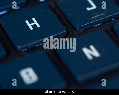 Tasti della tastiera retroilluminati blu con lettere h, j, n, b che mostrano polvere Foto Stock