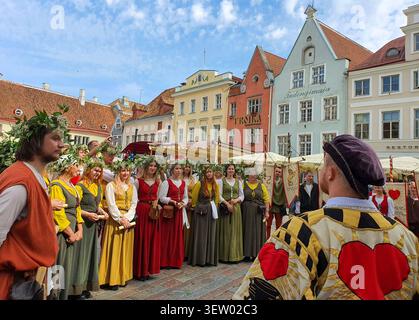 Tallinn, Estonia - 15 agosto 2020: Uomo in costume da gilda con motivi a cuore davanti alle donne in ghirlande floreali e abiti medievali, Medieval Days Foto Stock