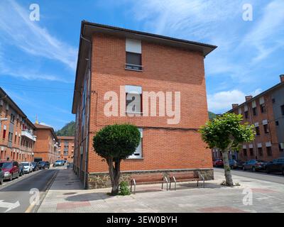EIBAR, SPAGNA - 25 MAGGIO 2025: Una strada tranquilla a Eibar, Spagna, fiancheggiata da edifici in mattoni, auto parcheggiate e lavanderia appesa alle finestre sotto Foto Stock