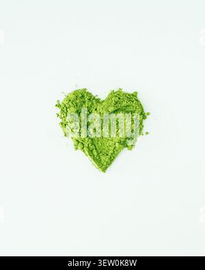 Forma a cuore verde in polvere matcha organica su sfondo bianco. Concetto di stile di vita sano e creativo. Un'idea di drink alla moda. Estetica Matcha. Posizione piatta Foto Stock