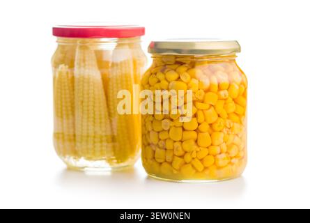 Due vasetti di vetro riempiti con chicchi di mais in scatola di colore giallo brillante e baby corn su uno sfondo bianco pulito, che mette in evidenza verdure conservate e cerotto di dispensa Foto Stock