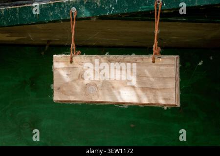 Insegna bianca in legno rustico appeso a funi con ragnatele su uno sfondo di legno verde scuro. Foto Stock